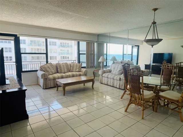 Tiled flooring throughout, wall of windows, glass panel balcony door, integrated wall mirror, and a ceiling-mounted light fixture