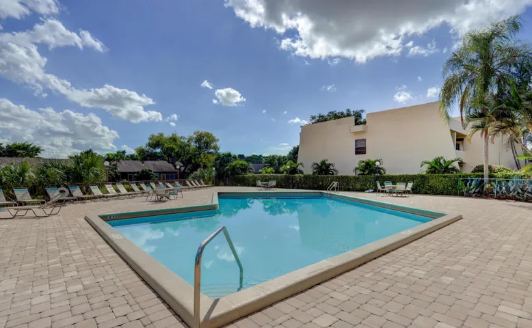 Expansive outdoor swimming pool featuring a paved surround and perimeter landscaping