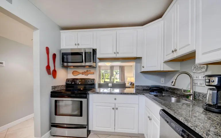White shaker-style cabinetry, granite countertops, stainless steel appliances, and a pass-through window