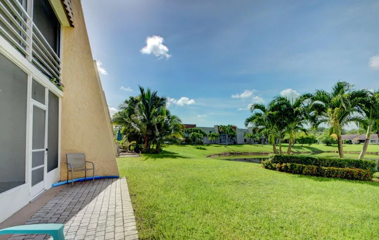 Expansive green space featuring mature palm trees and a pond