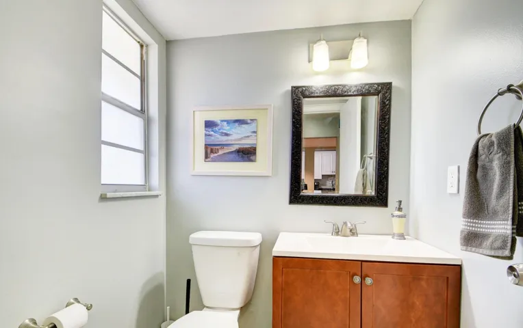 Corner vanity with a white countertop and wood-finish cabinetry