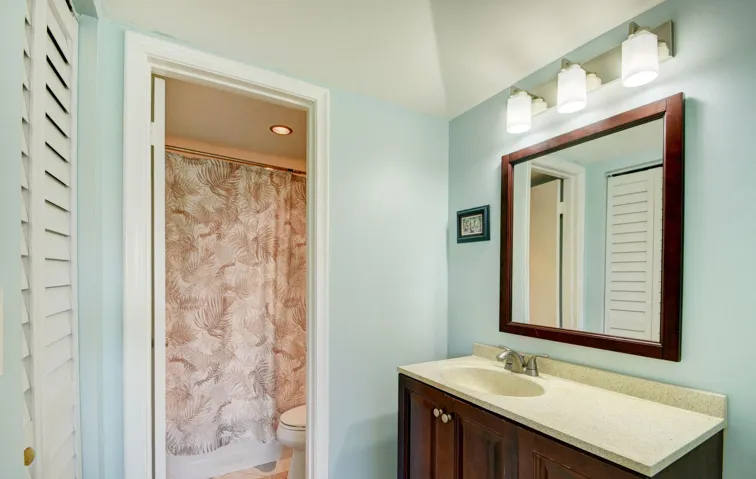 Vanity with a light-colored countertop, wood-finish cabinetry, and a framed mirror