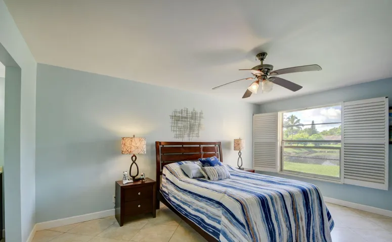 Recessed lighting, ceiling fan with integrated light fixture, window with louvered shutters, light-colored tile flooring, and a built-in closet