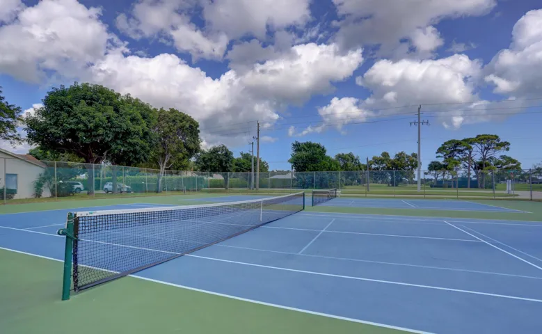 Tennis courts with blue and green surfacing and perimeter fencing