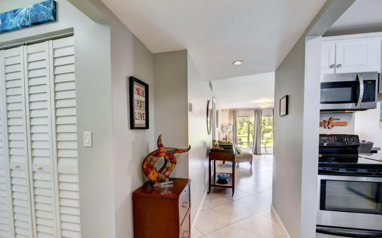 Hallway with tile flooring, recessed lighting, and louvered bifold doors