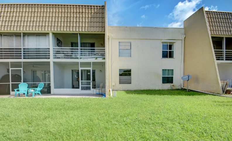 Expansive grass lawn with a two-story structure featuring a tiled roof and screened-in patios on both levels