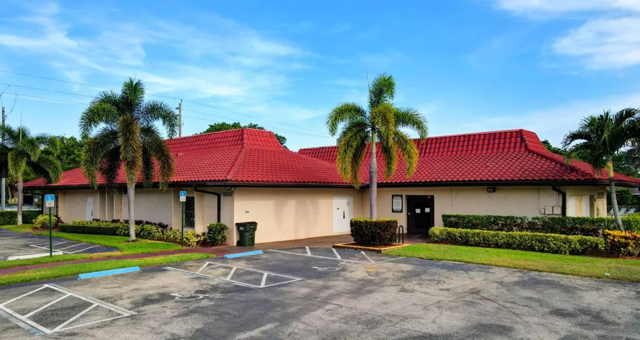 Building exterior with a red tiled roof, stucco finish, and an asphalt parking lot