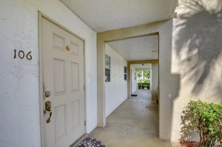 Entryway with a paneled door, brass hardware, and stucco exterior
