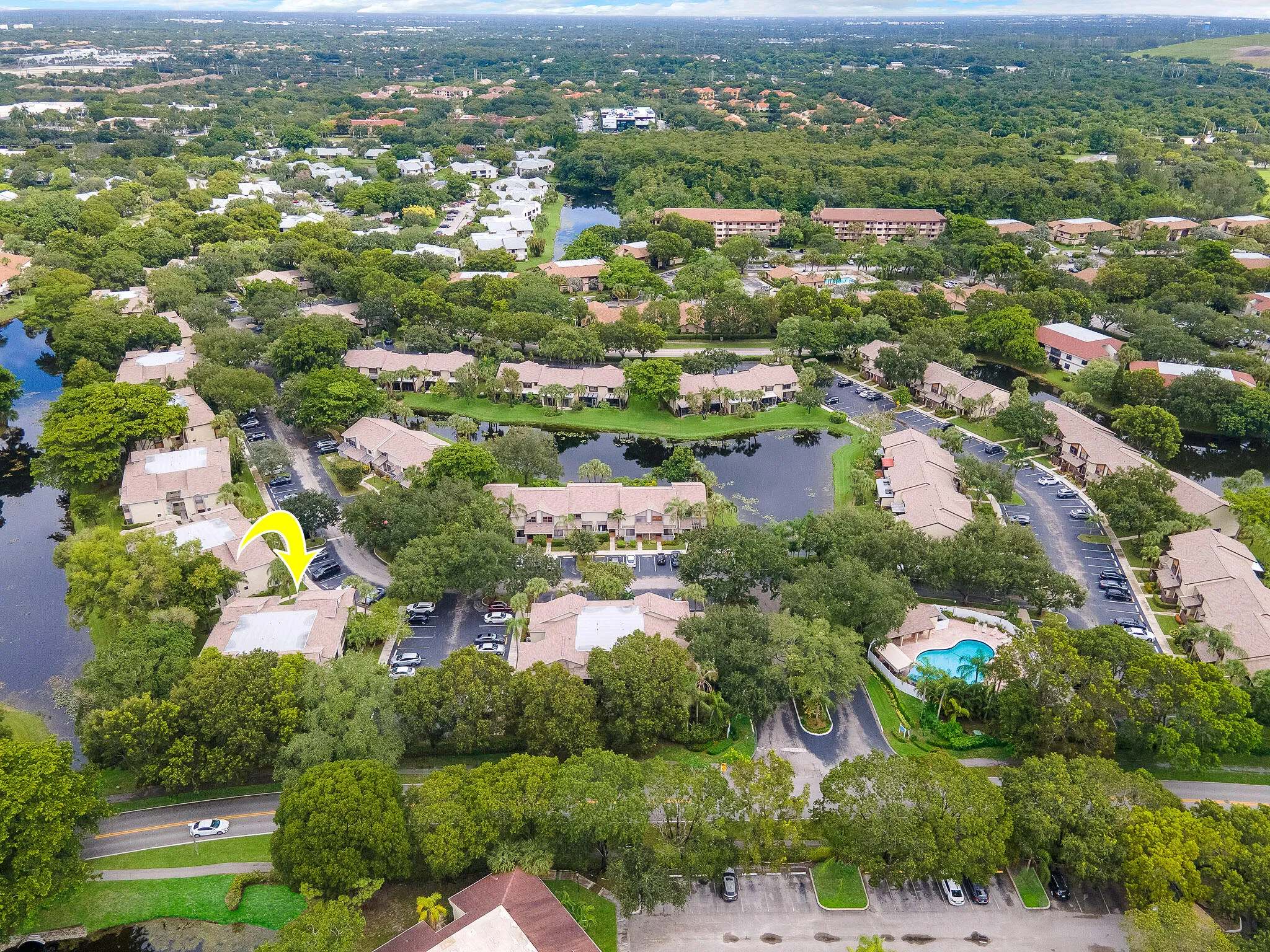 Community with mature landscaping, multiple water features, and a central community swimming pool with surrounding patio