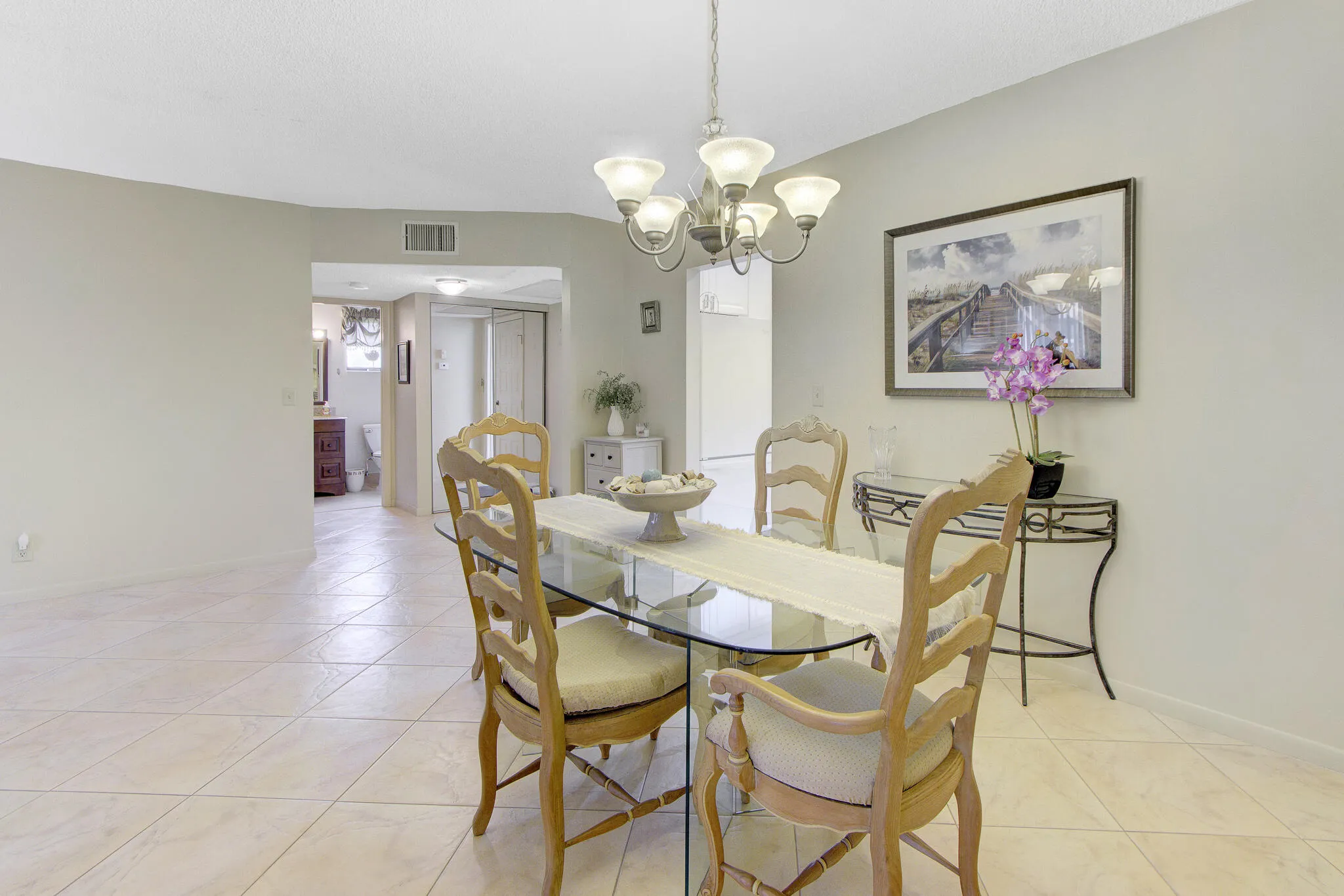 Tiled flooring throughout, recessed lighting in the hallway, and a chandelier fixture