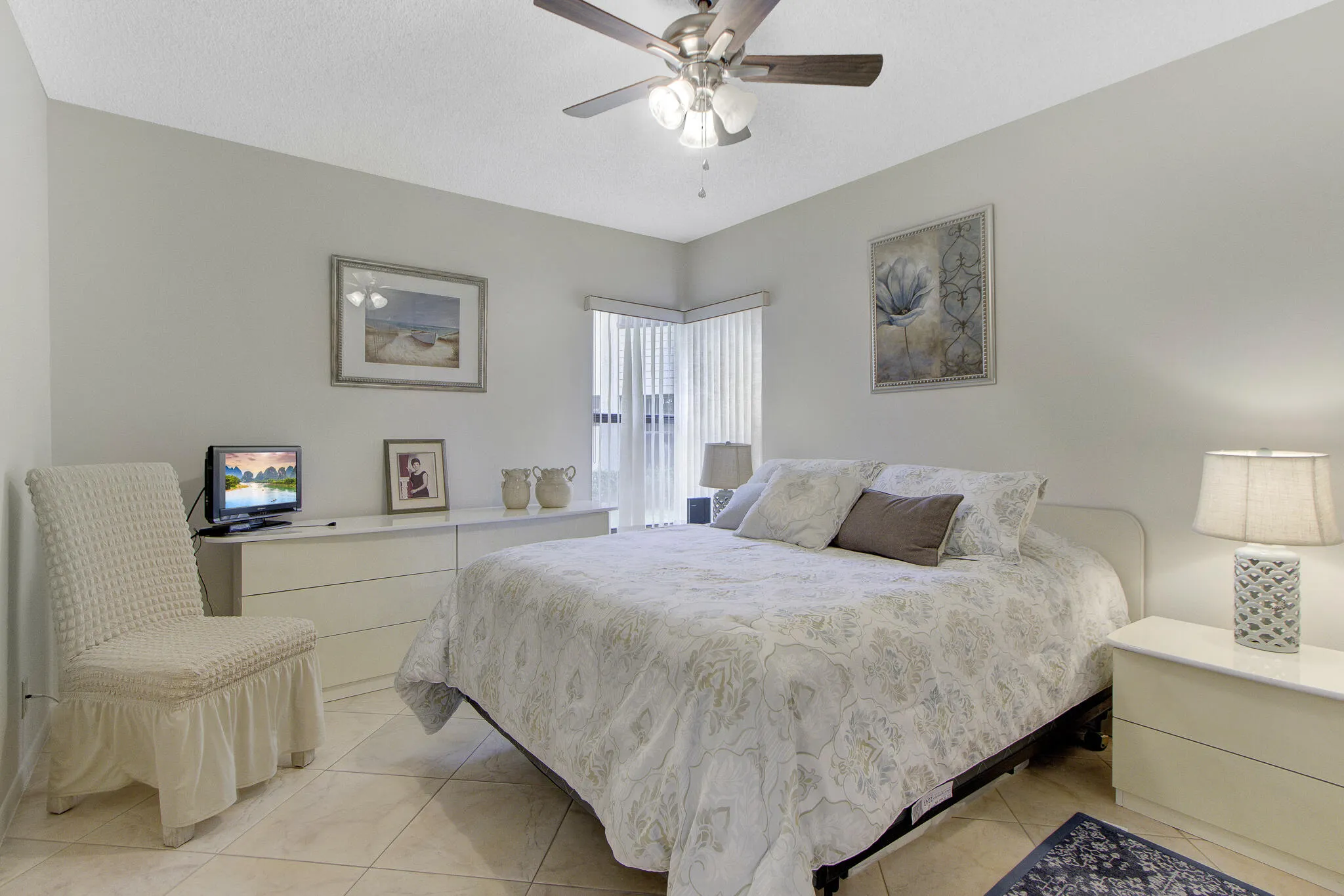 Ceiling fan with integrated lighting, tile flooring, window with vertical blinds, neutral wall paint, built-in dresser