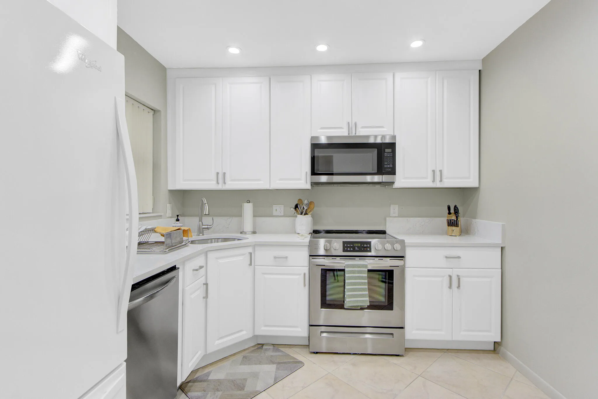 Kitchen featuring white cabinetry, light-toned countertops, stainless steel appliances, recessed lighting, and tile flooring