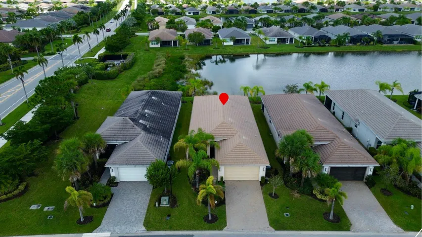 Aerial perspective of residences featuring tile roofs, mature landscaping, and an adjacent waterway
