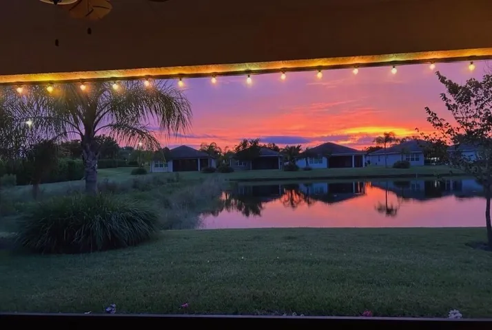 Screened lanai featuring brick paver flooring, a ceiling fan, string lighting, and a water-facing orientation