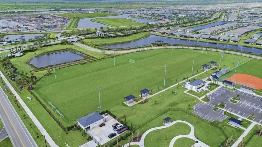 Expansive green spaces featuring multiple sports fields, a baseball diamond, and paved walking paths