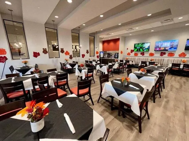Spacious dining area featuring wood-finish flooring, recessed lighting, wall-mounted display screens, and a service counter with built-in appliances