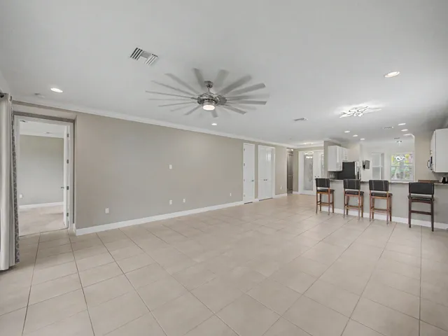 Spacious room featuring neutral tile flooring, recessed lighting, a modern ceiling fan, and crown molding