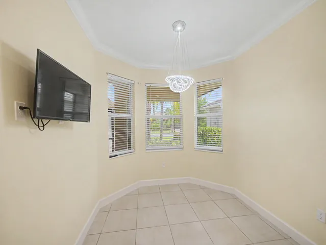 Bay window area featuring three windows with blinds, a contemporary chandelier, and tile flooring