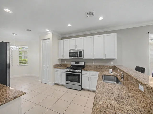 Kitchen featuring granite countertops, white cabinetry, stainless steel appliances, tile flooring, and recessed lighting