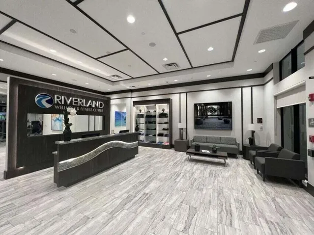 Recessed lighting illuminating a decorative ceiling, front desk with an accent light strip, and gray-toned plank flooring