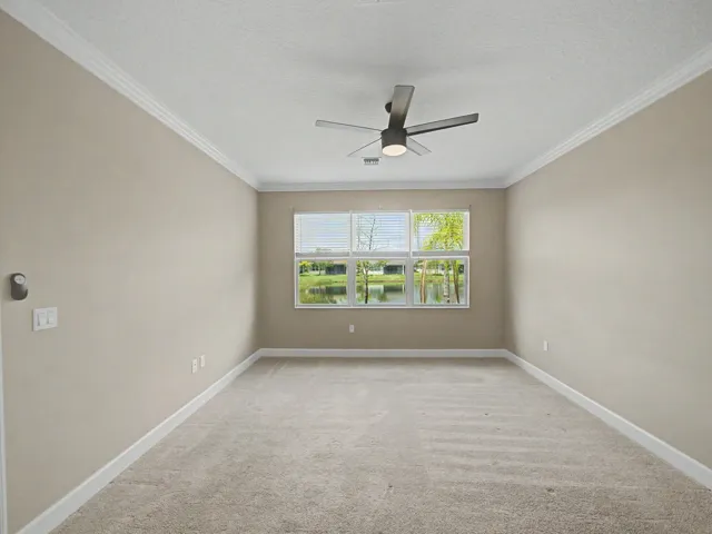 Neutral wall tones with crown molding, carpeted flooring, and a ceiling fan