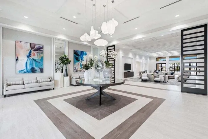 Spacious foyer featuring coffered ceilings, modern pendant lighting, and decorative wall paneling