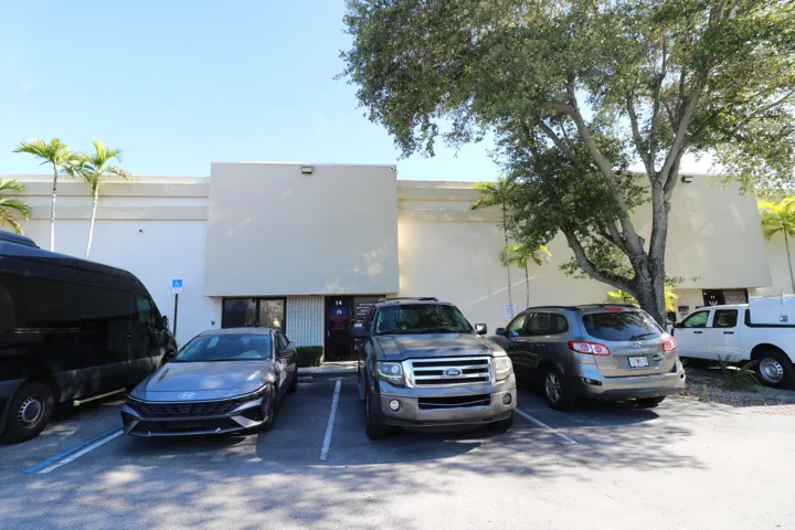 Exterior featuring a light-colored stucco finish, multiple entry points, and mature trees