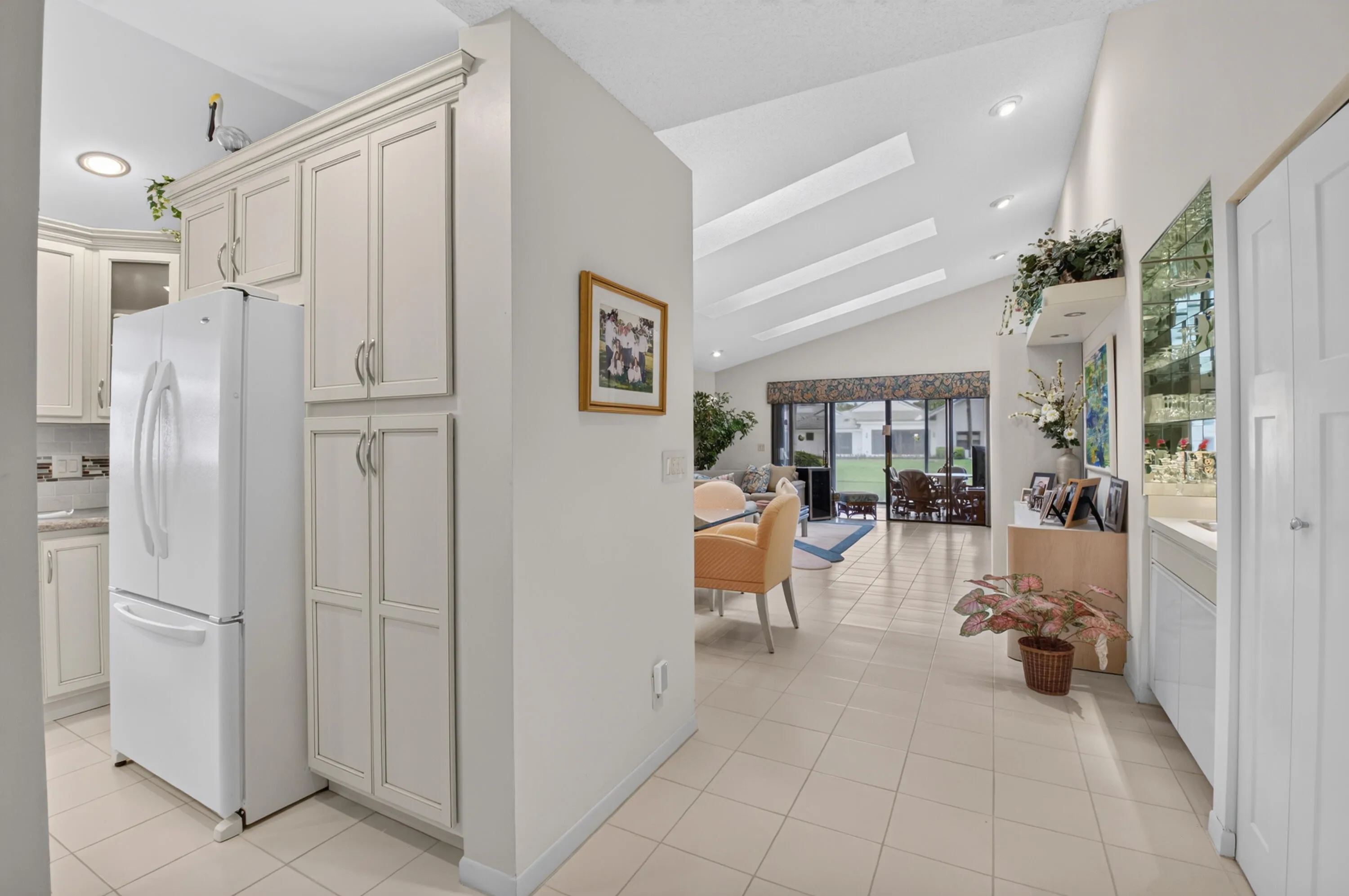 Vaulted ceilings with recessed lighting, large format floor tiling, white built-in cabinetry, and integrated shelving