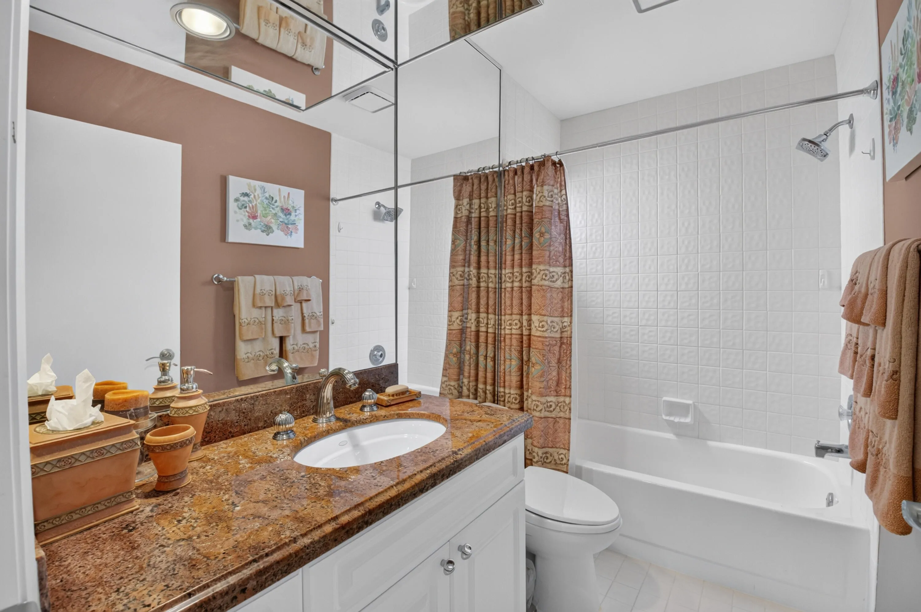 Bathroom featuring a single vanity with a patterned countertop, white cabinetry, an undermount sink, and a mirrored wall