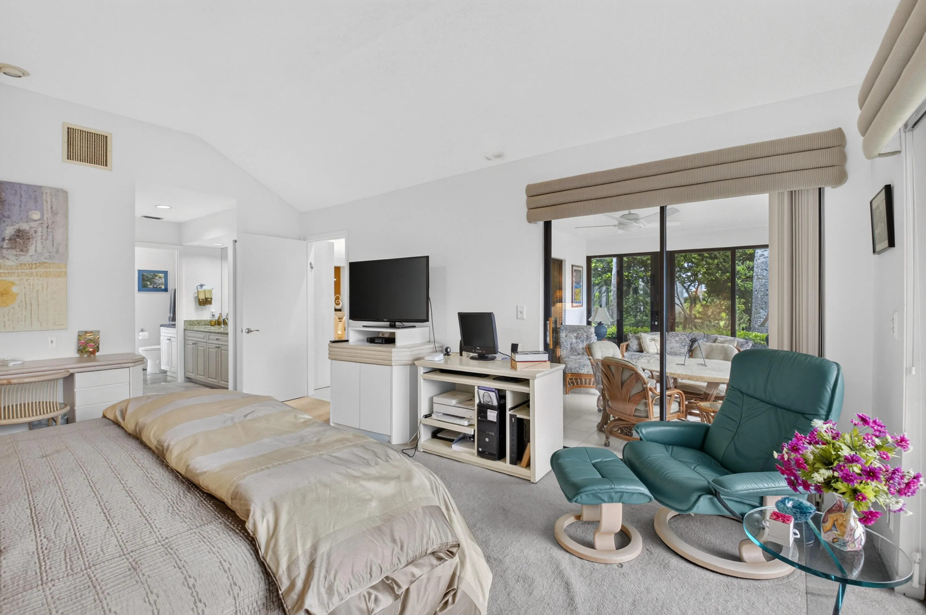 Vaulted ceilings, carpet flooring, sliding glass doors, and a bathroom with a vanity