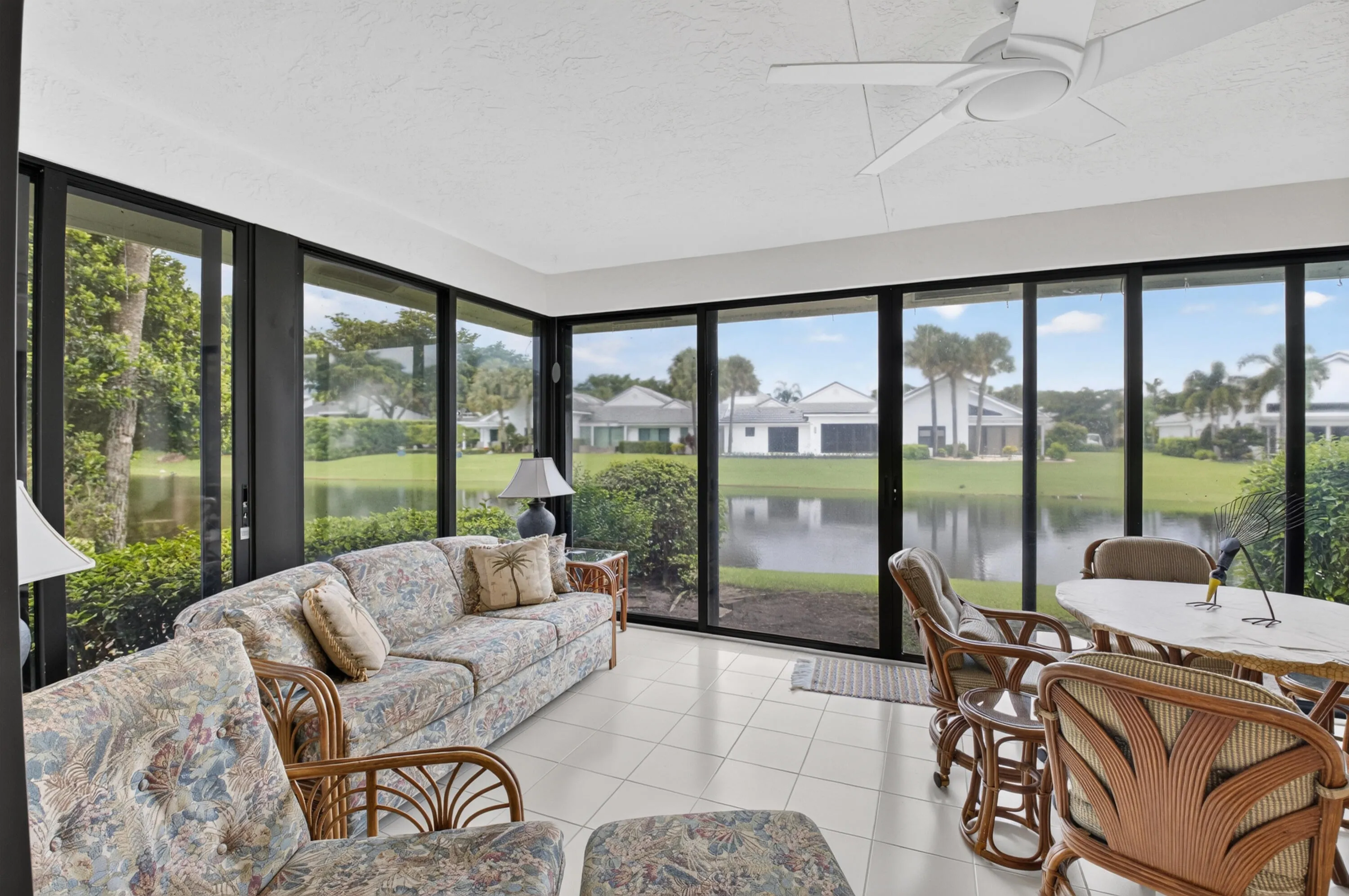 Sunlit sunroom with expansive sliding glass doors and transom windows framing water and landscape vistas