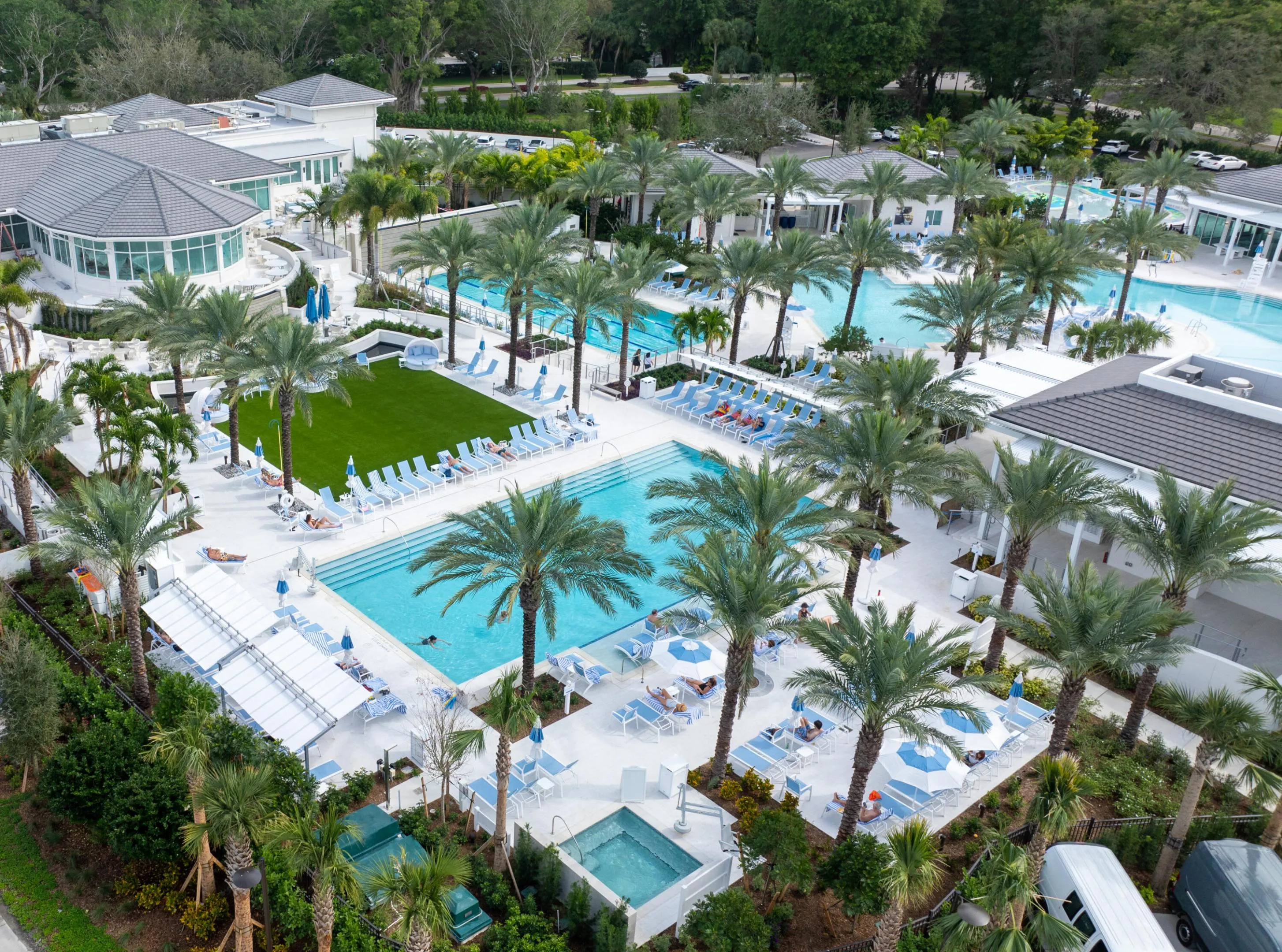Multiple pools with expansive sundecks, mature palm trees, a spacious turf lawn, and a spa area