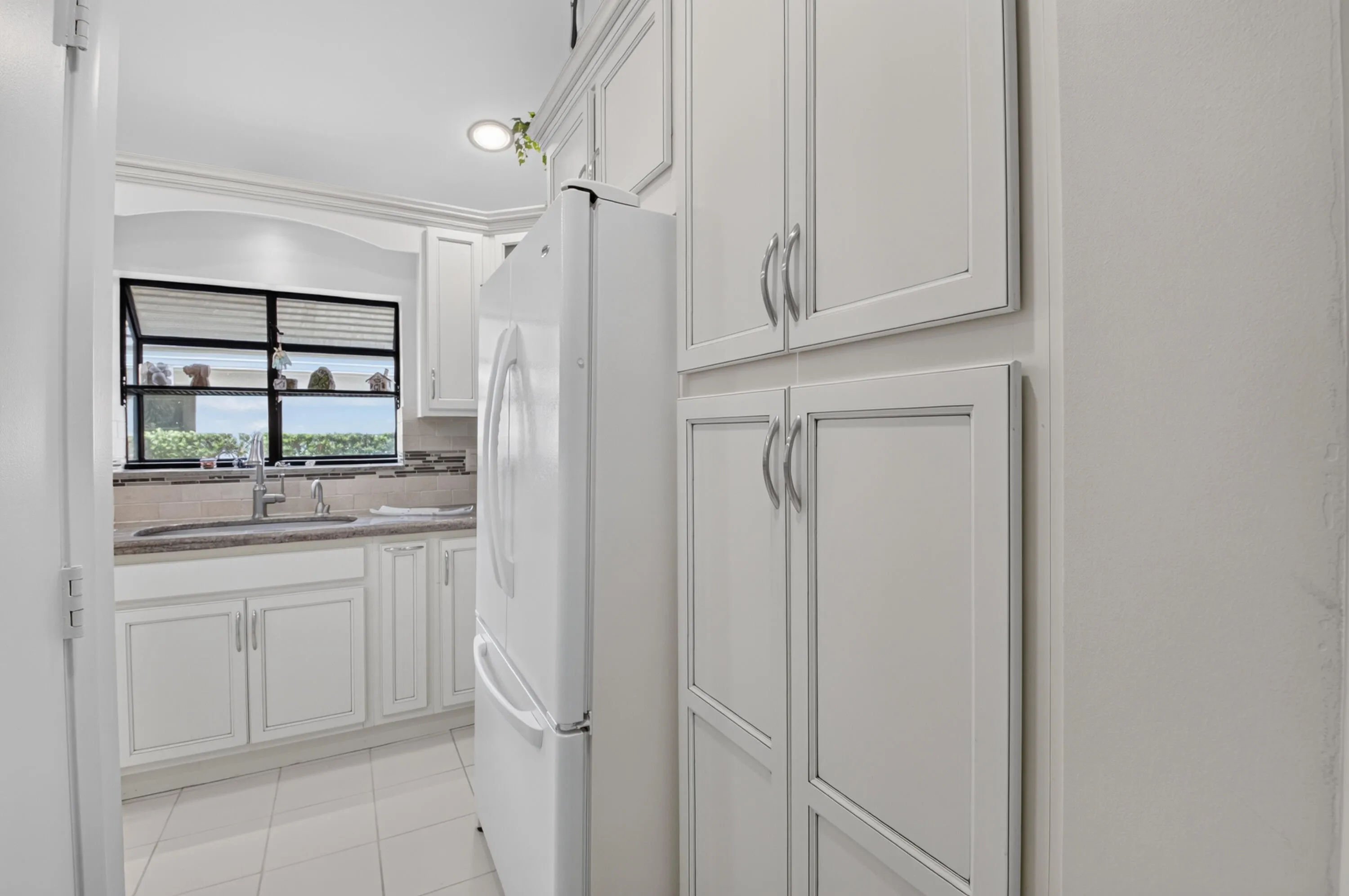 White shaker-style cabinetry, tile flooring, built-in storage, and a stainless steel sink with a single-handle faucet