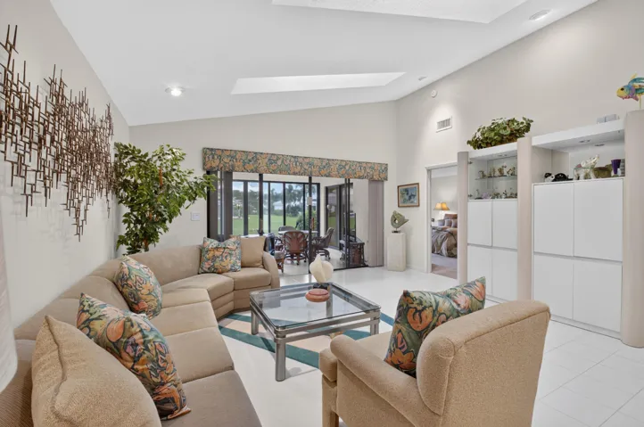 Bright, open living area featuring a curved sectional sofa arrangement, glass-top coffee table, and abundant natural light from multi-panel glass doors