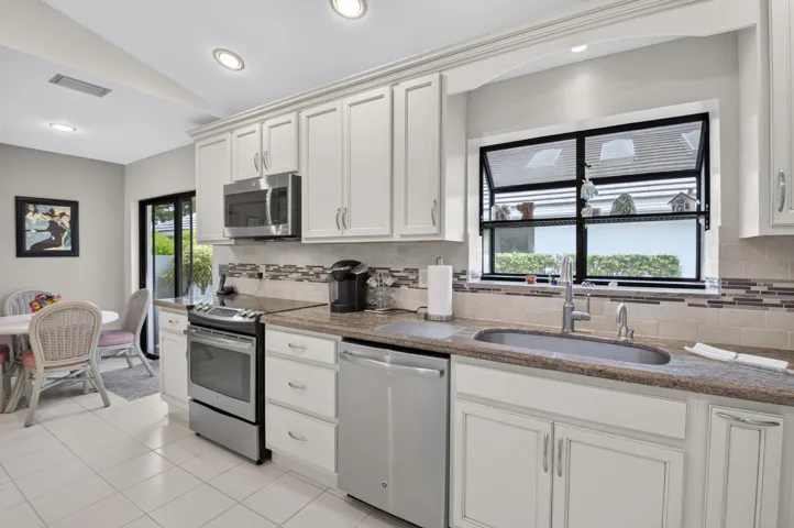 Kitchen featuring white cabinetry, stainless steel appliances, a tiled backsplash, a built-in sink, and recessed lighting