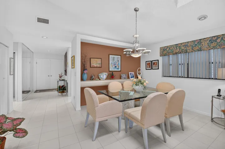 Recessed lighting throughout, tile flooring, built-in shelving, window with vertical blinds, and a chandelier lighting fixture