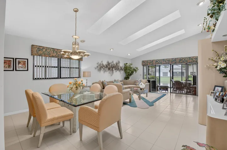 Vaulted ceilings with recessed lighting, large glass slider, ceramic tile flooring, and a dining area chandelier