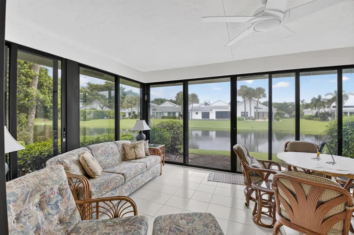 Sunlit sunroom with expansive sliding glass doors and transom windows framing water and landscape vistas