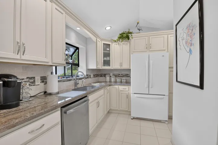 Kitchen featuring cream cabinetry, stainless steel dishwasher, undermount sink, recessed lighting, and tile flooring