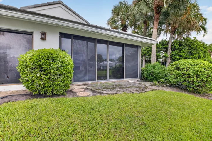 Modern residence showcasing expansive manicured lawn, mature palm trees, and professionally landscaped foundation plantings
