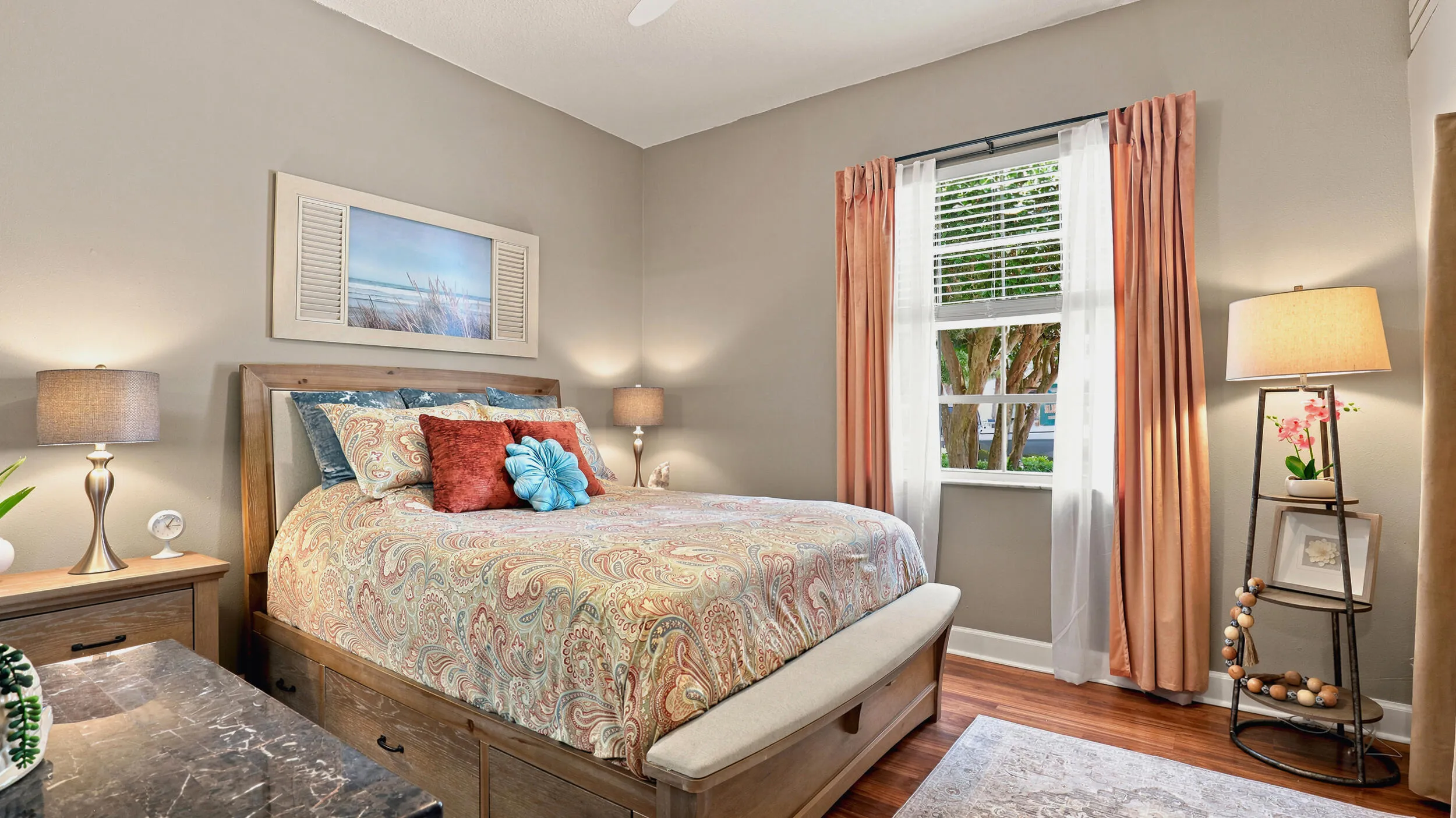 Comfortable guest bedroom with wood flooring, ceiling fan, and plenty of natural light.
