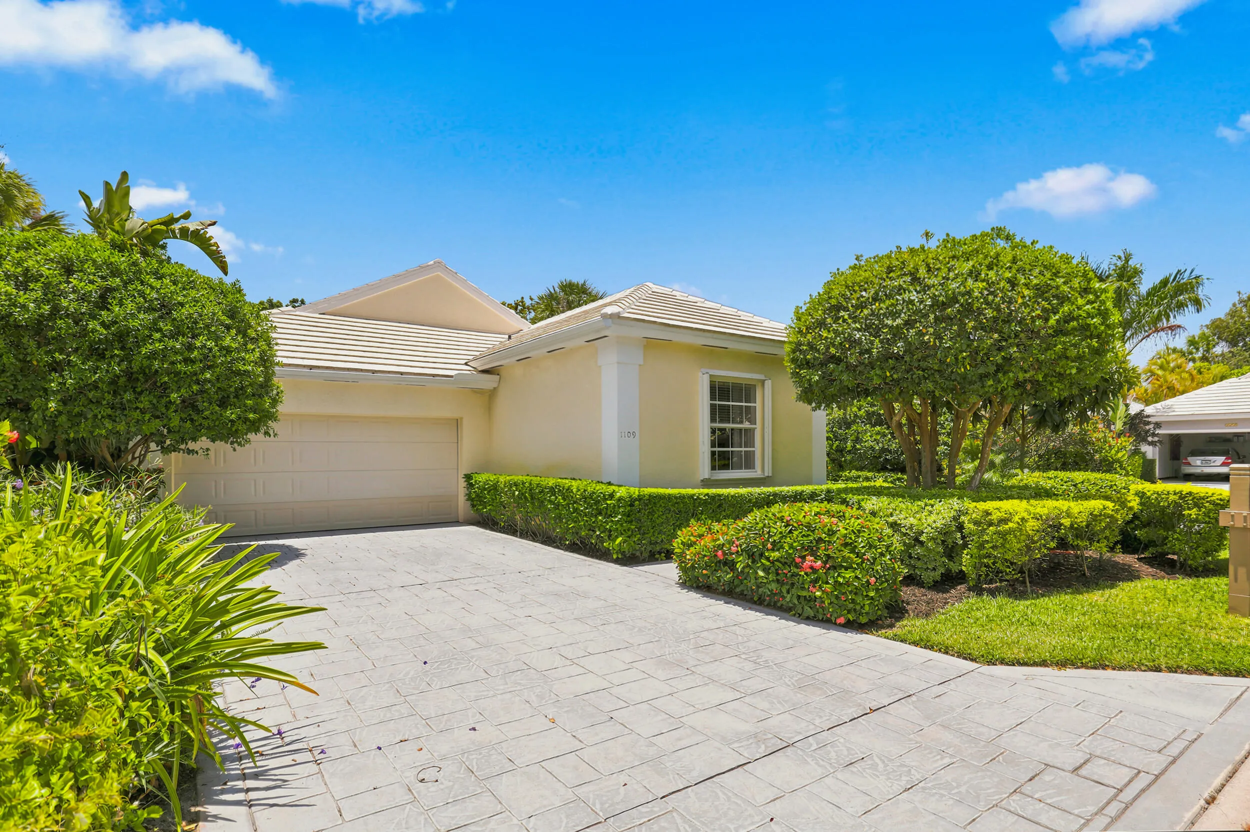 Additional front view showcasing the paver driveway, mature landscaping, and inviting curb appeal.