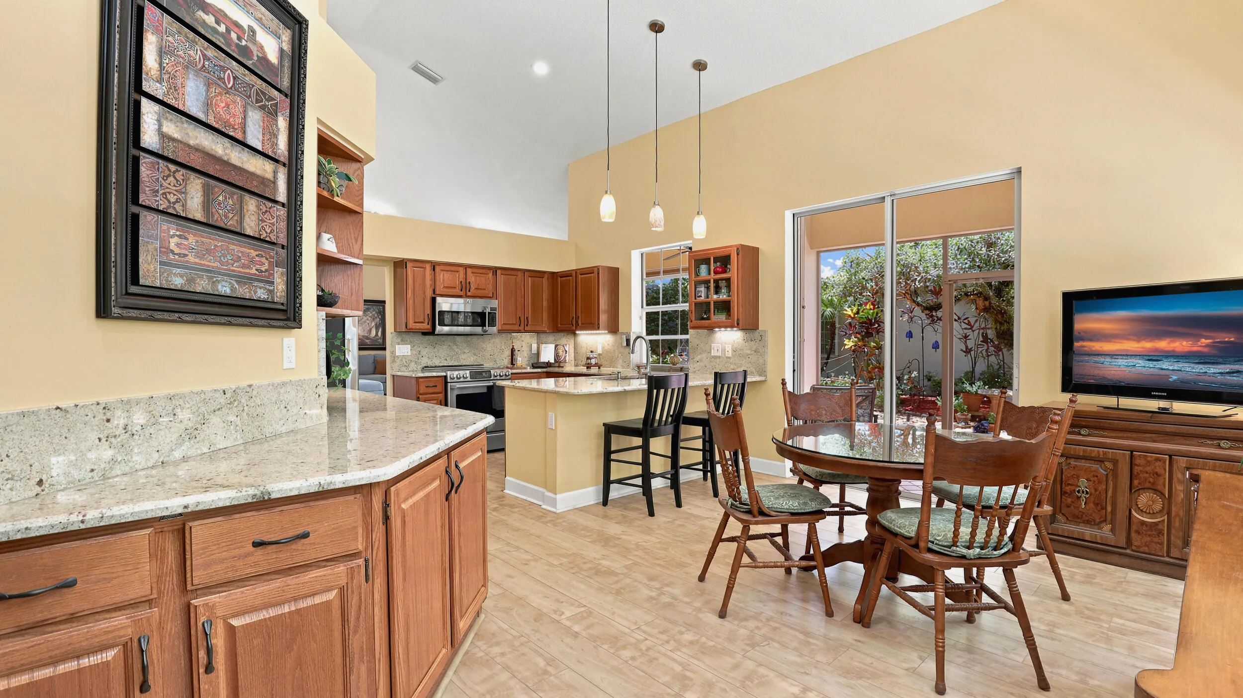Wide view showcasing the kitchen, breakfast bar, and adjacent casual dining space.