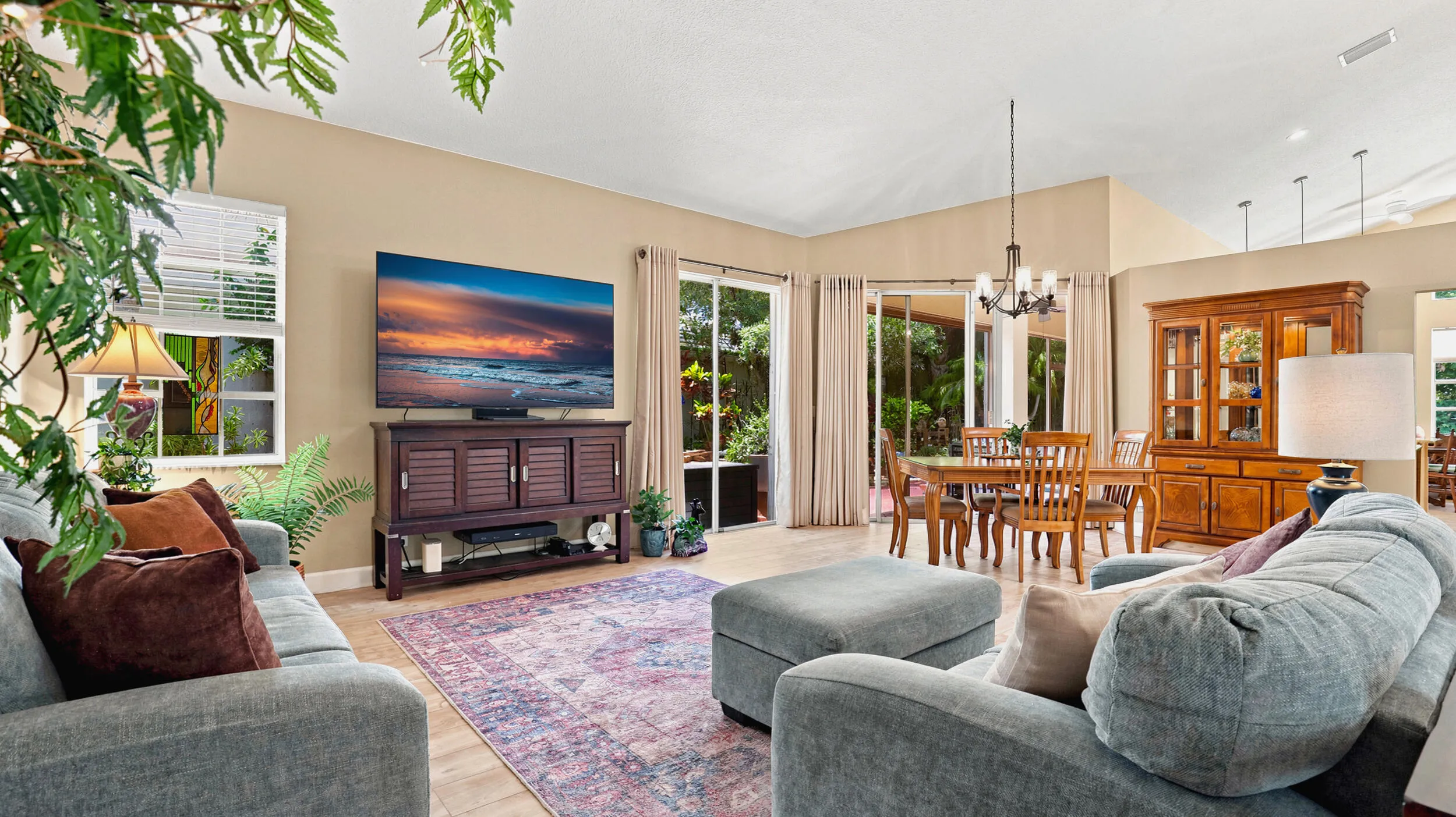 Bright living space featuring vaulted ceilings and sliding glass doors overlooking the landscaped outdoor area.