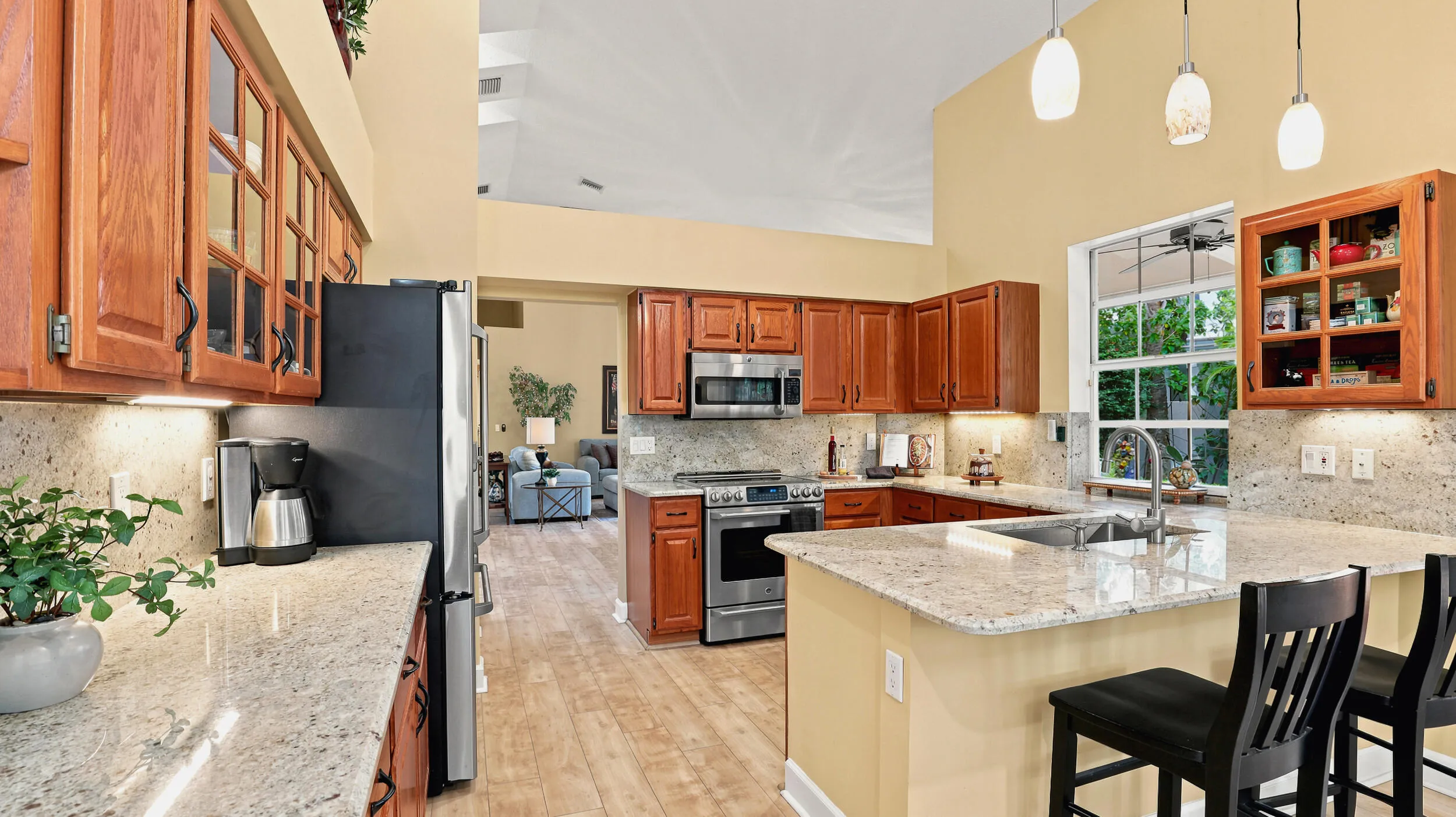 Spacious kitchen featuring warm wood cabinetry, granite countertops, stainless steel appliances, and island seating.