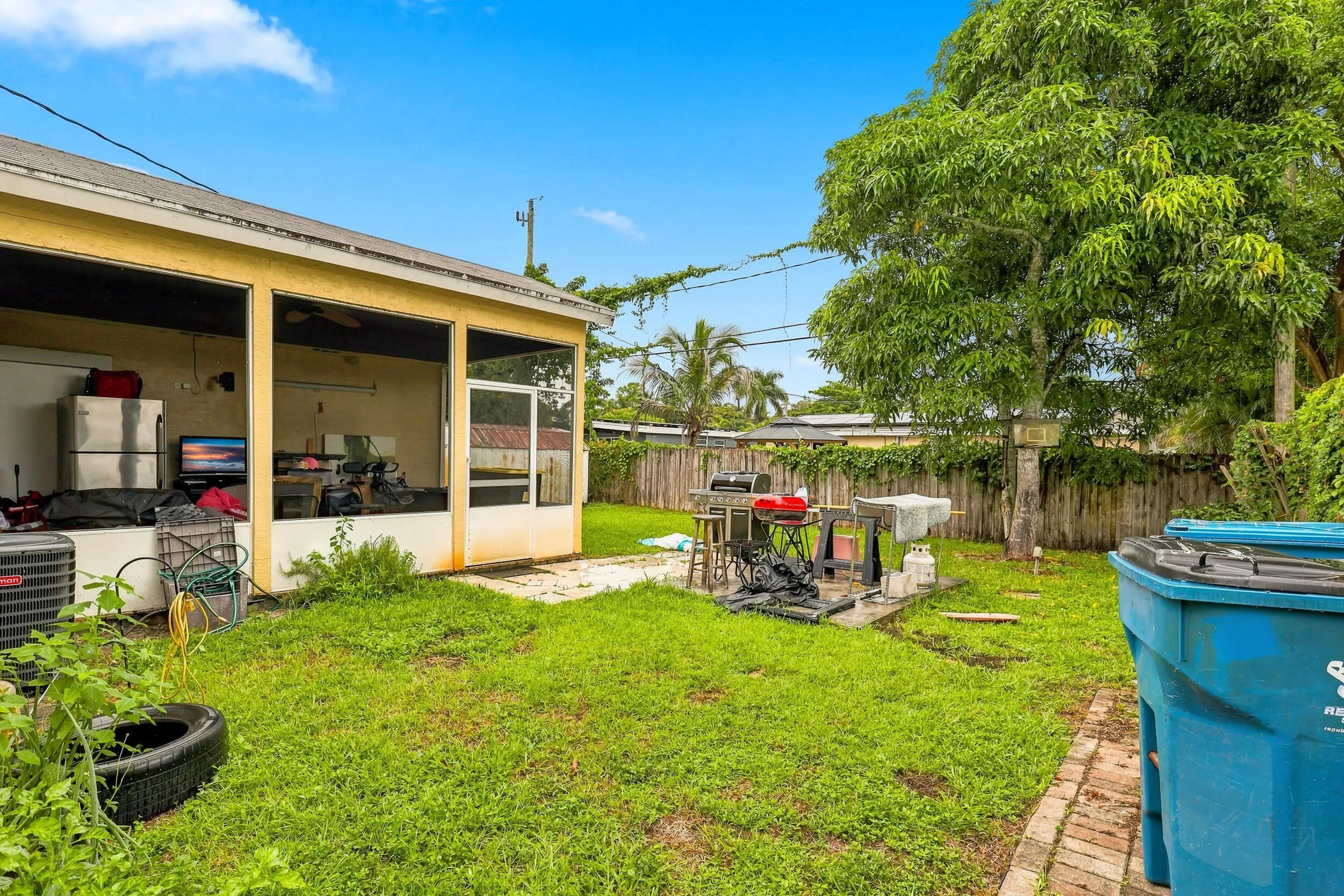 Rear yard view showcasing the covered patio, grassy outdoor space, and mature landscaping.
