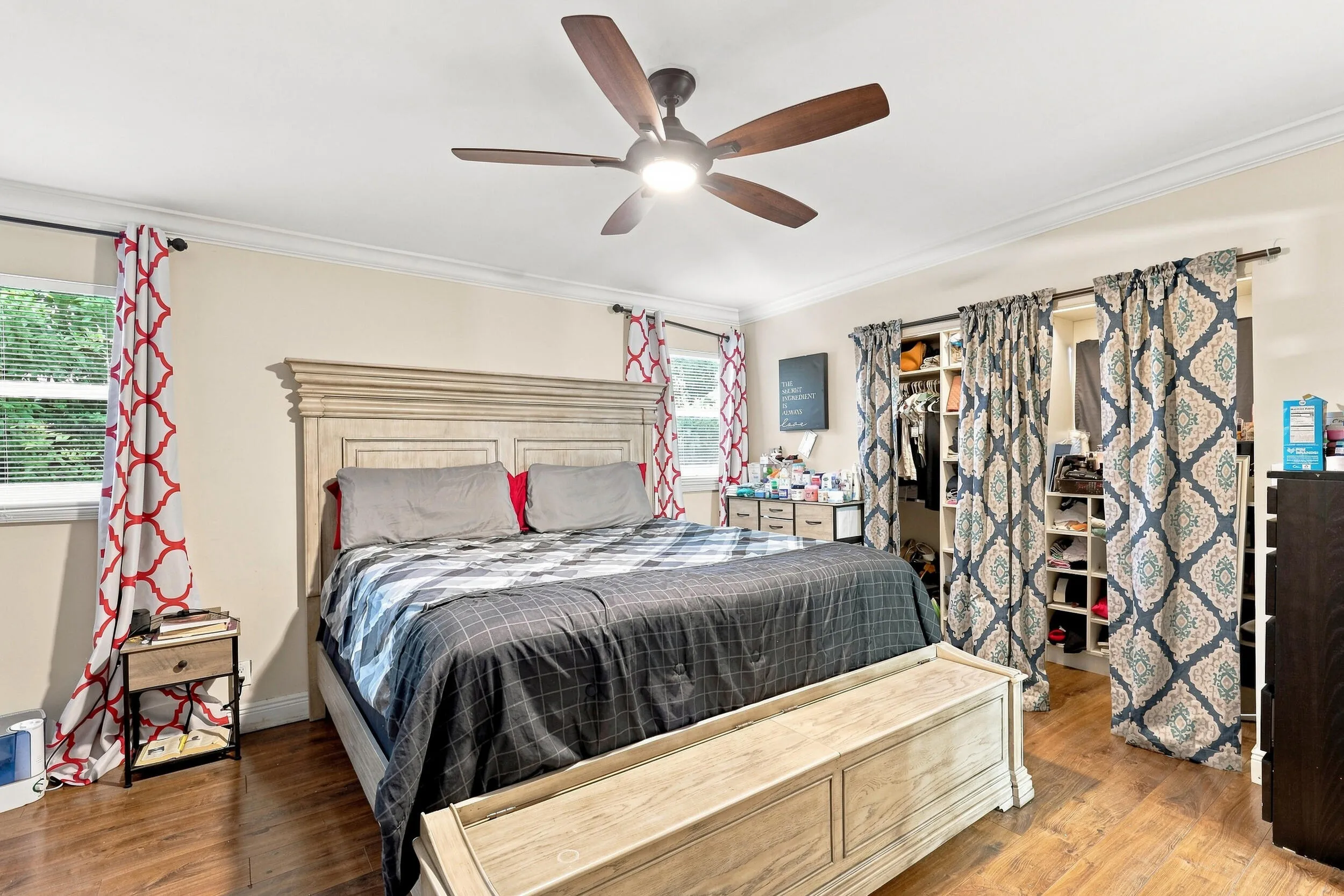 Comfortable bedroom with wood-look flooring, ceiling fan, and natural light.