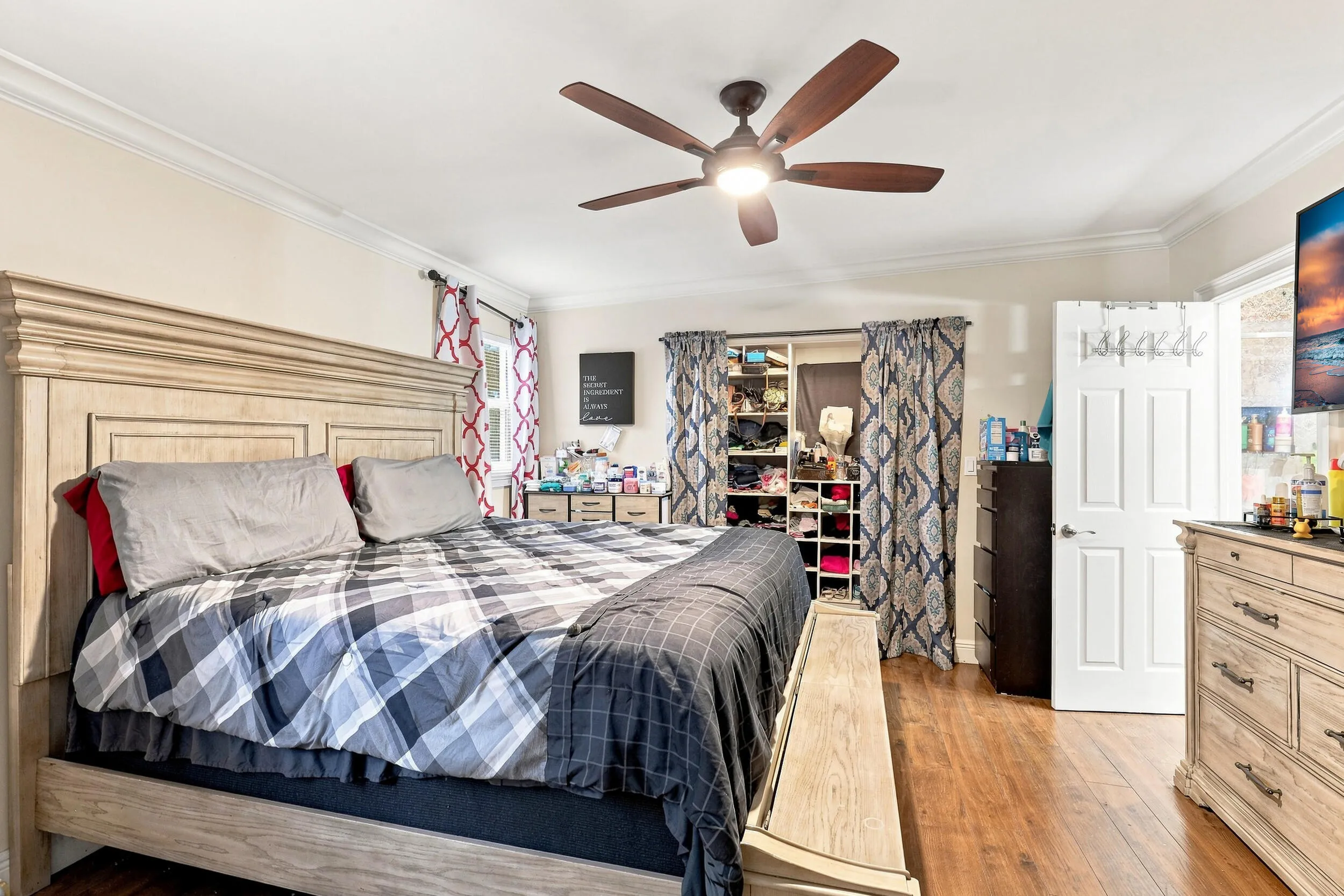 Generously sized primary bedroom with wood-look flooring, ceiling fan, and ample space for furnishings.