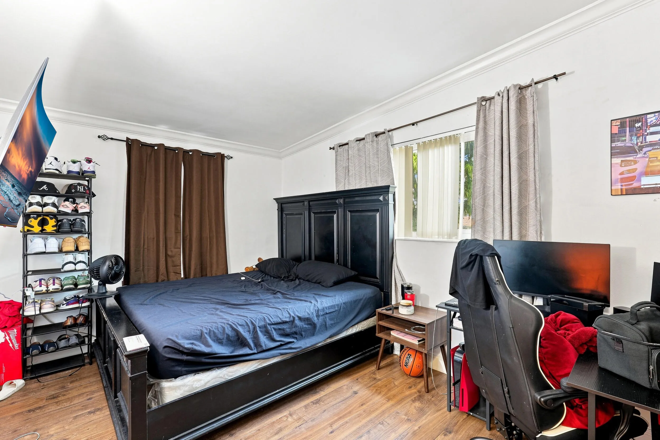 Comfortable bedroom with wood-look flooring, natural light, and space for a desk or workspace.