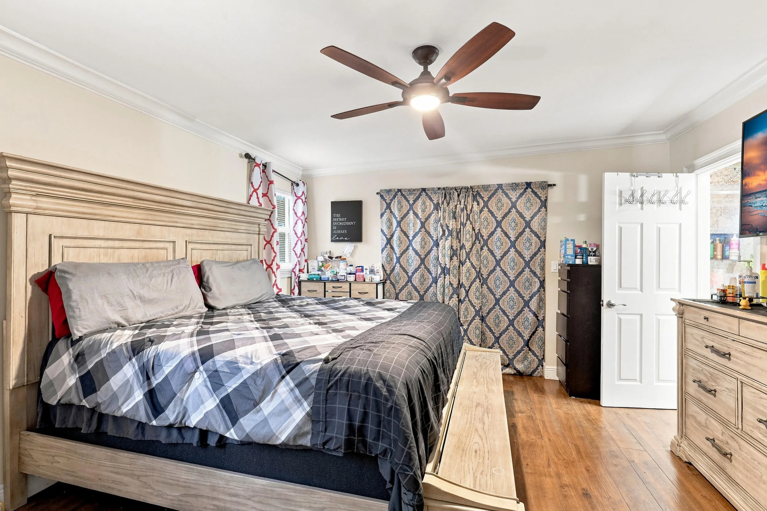 Spacious primary bedroom with wood-look flooring, ceiling fan, and generous storage.